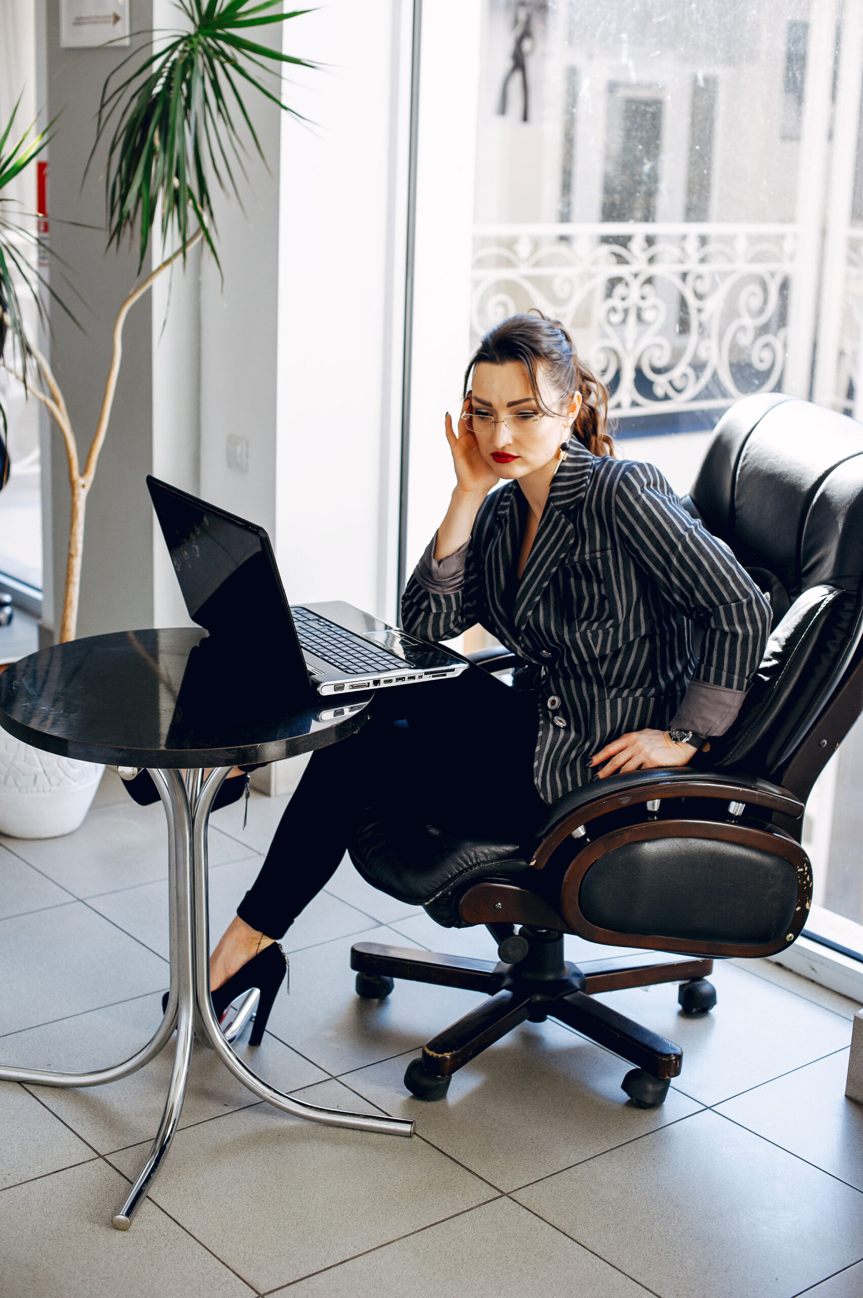 Mujer sentada cómodamente en una silla ergonómica frente a su ordenador en una moderna oficina, mostrando un ambiente de trabajo saludable y productivo.